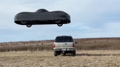 A black car flying over an SUV in a field 