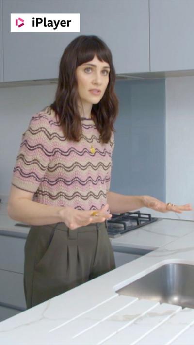 Tuppence Middleton stands in a white kitchen in front of the sink