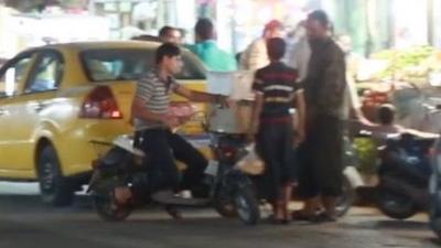 Picture shows a group of men passing by a market.