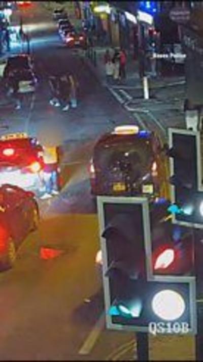 A car being driven along a street at night-time. There are other vehicles and pedestrians around.