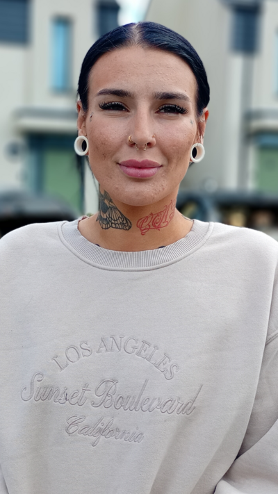 Elise Conroy is a young woman with slicked back dark hair and stretchers in her ears. She is smiling at the camera. She is wearing a cream jumper.