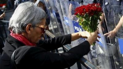 A demonstrator holds flowers before a police barricade during a commemoration for the victims of Saturday's bomb blasts in the Turkish capital, in Ankara, Turkey, 11 October 2015