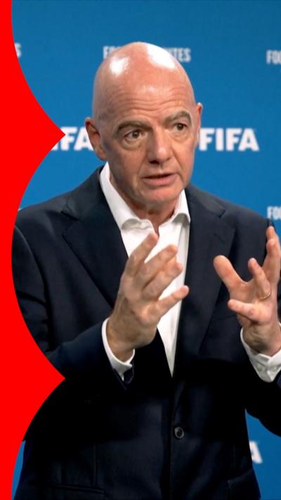 Gianni Infantino standing against a blue Fifa hoarding