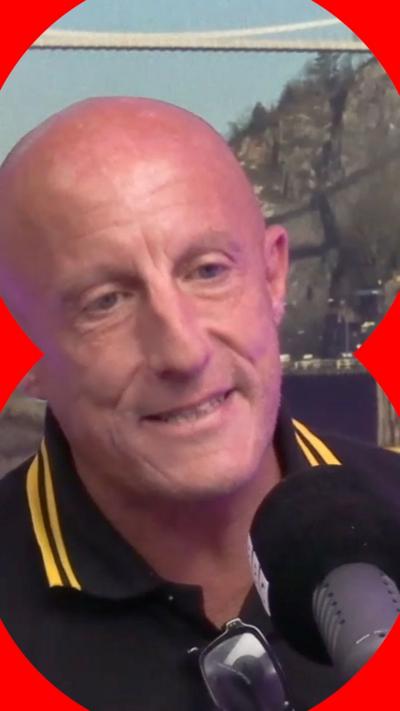 A man with a bald head talks into a microphone