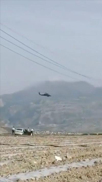 A US helicopter flying in Iran, over a white car with three people stood around it