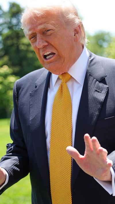 Donald Trump wears a dark navy blue suit and yellow tie as he speaks to reporters (off camera) outside the White House.