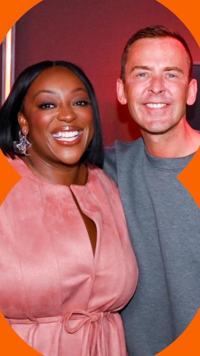 Judi Love and Scott Mills smile with their arms around each other in a Radio 2 studio