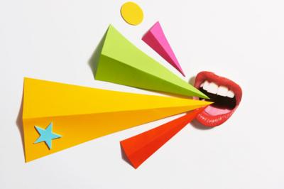 An open mouth with folded triangles of coloured paper pointing into it