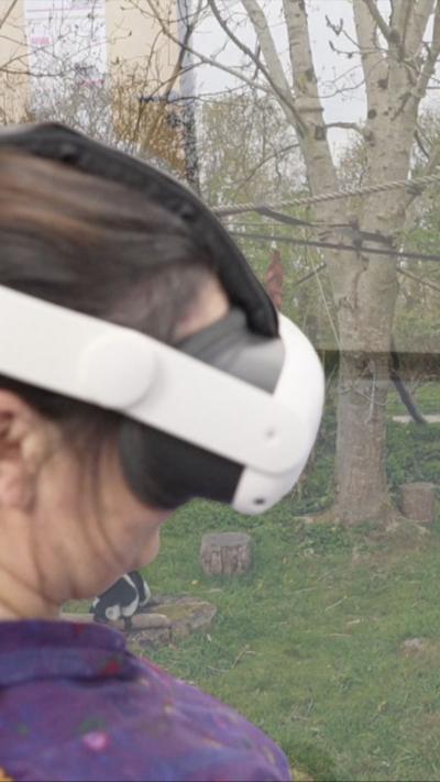 A woman wearing a VR headset with trees behind her