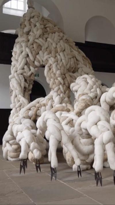 A sculpture with tendrils, made out of wool and horse hair in an empty room with white walls