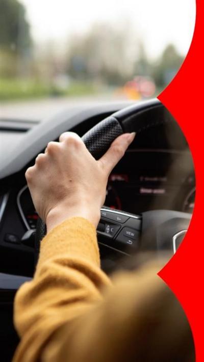 Rear seat view of woman in yellow jumper driving a car.