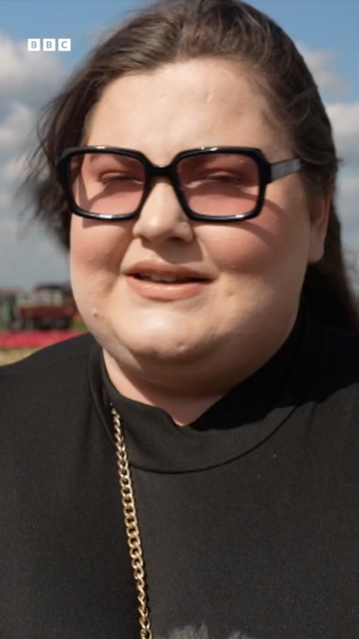 A woman with dark hair and thick rimmed glasses speaks to a BBC reporter
