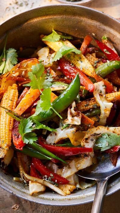 Top down view of stir fry jalfrezi in a wooden handled pan
