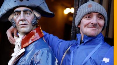 Sonny smiles, standing next to a historical statue