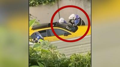 Police surround yellow car, with one officer pointing their gun in the window