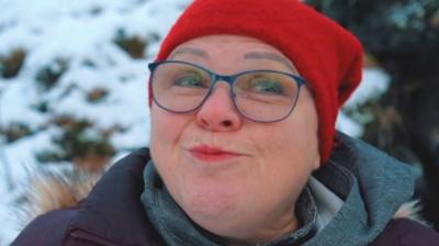 A woman wearing glasses and a red beanie hat