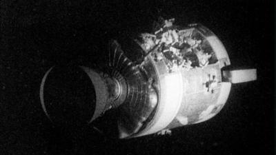 Apollo 13 service capsule is pictured with damage to its side.