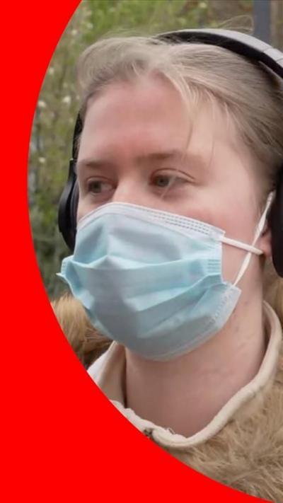 A blonde woman in a surgical face mask