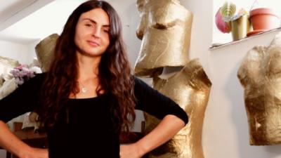 Artist standing in front of the gold torso casts