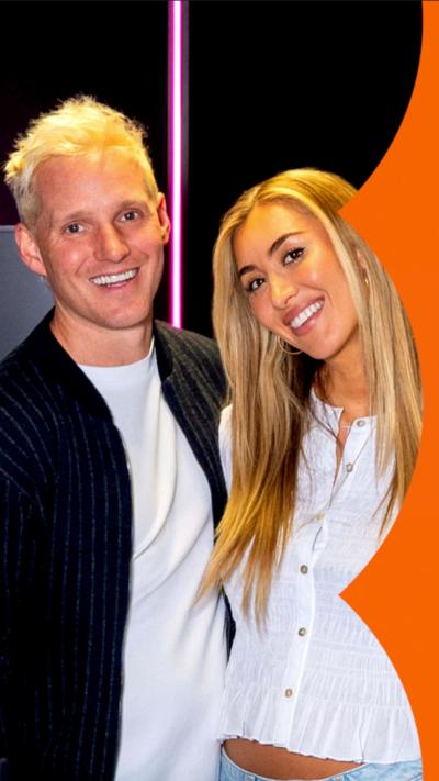 Jamie Laing and Sophie Habboo stand together smiling - he has short blond hair and wears a black shirt over a white top; she has long blonde hair and wears a white shirt 