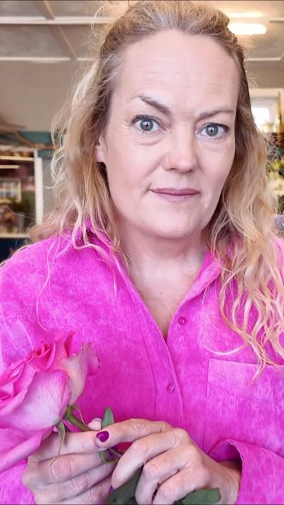 Woman wearing pink and wearing a pink flower. 