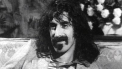 Frank Zappa sittting on a couch being interviewed