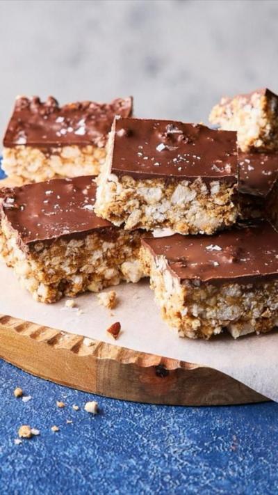 Square rice cake bites topped iwth chocolate on a wooden plate
