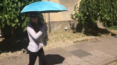 Emma shading herself under an umbrella