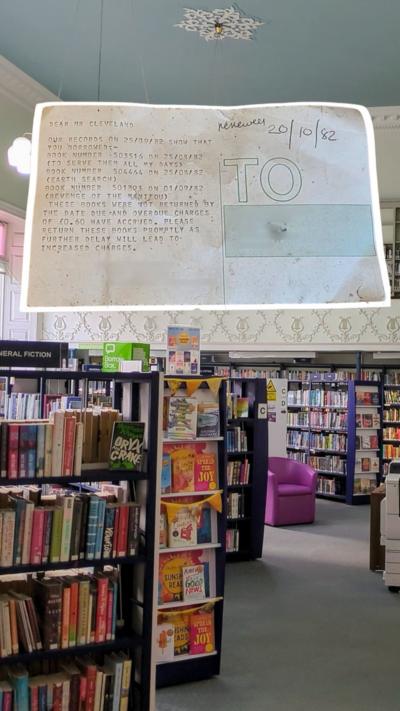 A library with multiple bookshelves with a highlighted piece of paper above