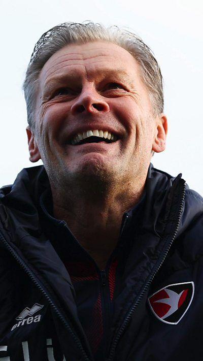 Man with grey hair smiling and wearing sportswear
