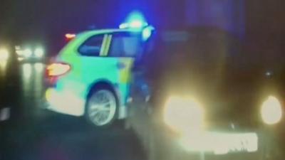A police car is shown next to a car that had driven down the wrong side of the road before being stopped