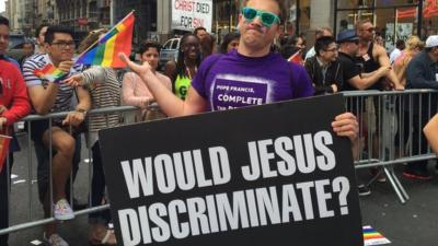 A protestor with a signing saying "Would Jesus discriminate?"