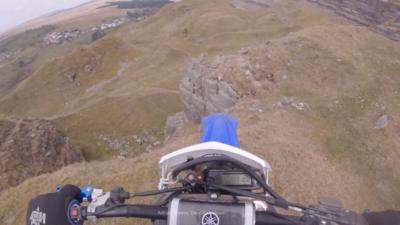 Handlebars of a motorcross bike before it is driven off the edge of a quarry