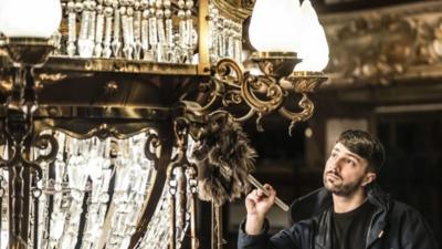 Tower ballroom team member Josh Taylor cleans one of Blackpool Tower"s two huge chandeliers