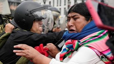 Indigenous woman clashing with line of police officers