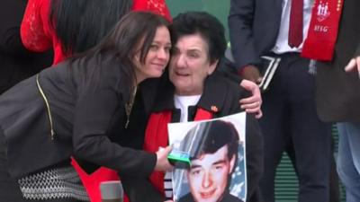 Relatives hugging and holding large photo of a relative who was killed at Hillsborough