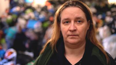 Organiser Magda looks at the camera, with bags of donated goods visible in the background.