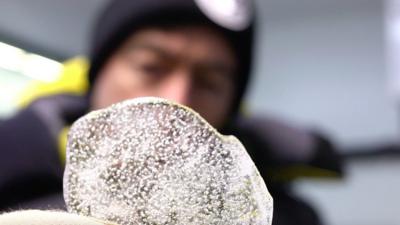 Piece of ice with bubbles in it, being held by a scientist