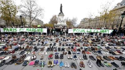 Banners which read "Paris marches for climate change" are displayed in front of pairs of shoes placed at the Place de la Republique in Paris