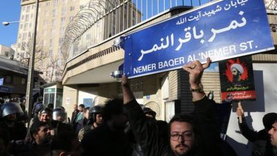 An Iranian holds a street sign bearing the name of Shia cleric Nimr al-Nimr during a demonstration against his execution by Saudi authorities