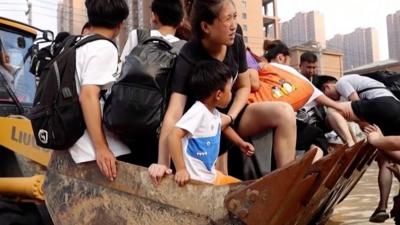 People in the bucket of a bulldozer