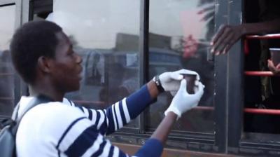 A man giving a drink to a commuter on a bus