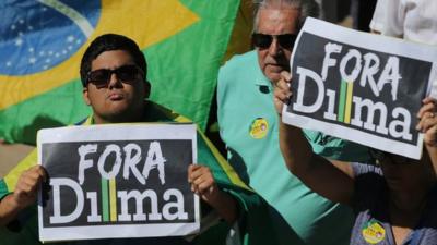 Demonstrators hold signs that read "Dilma Out" n Portuguese during a protest against the government on 16 August 2015