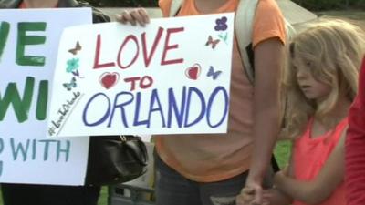 Girl and parent with a sign saying Love to Orlando