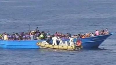 A fishing boat filled with people being rescued