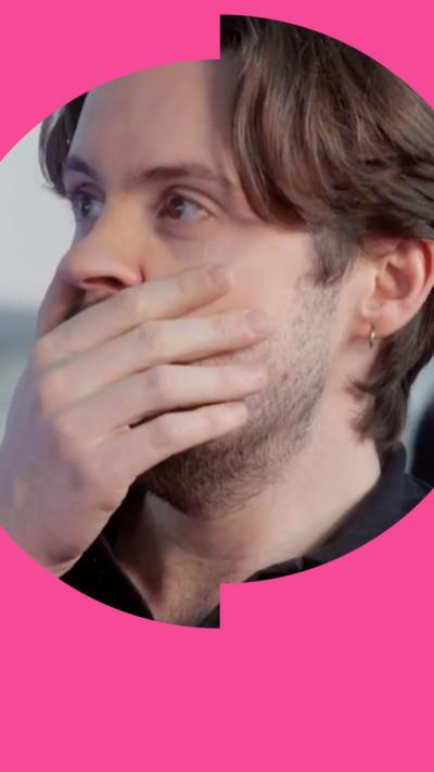 A man with short, dark hair covers his face