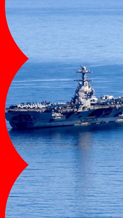 A large grey warship on open water with many military aircraft on board.