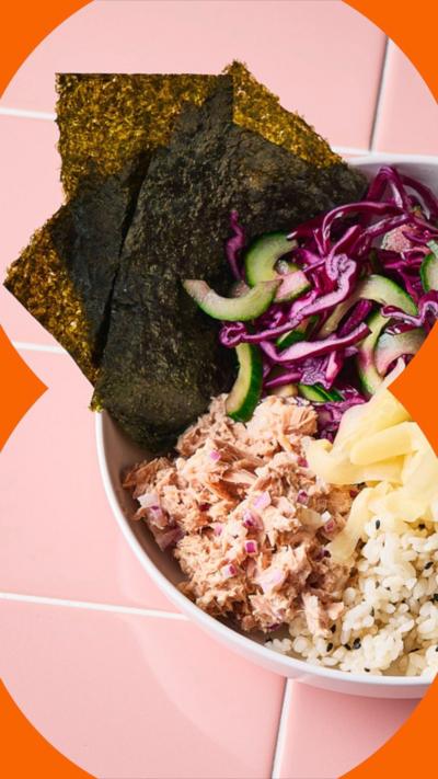 a bowl of rice, tuna, salad and seaweed wraps, viewed from above, on pale pink tiles.