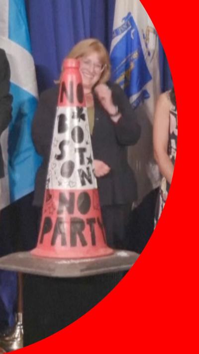Traffic cone with graffiti on it and woman standing behind it smiling. 