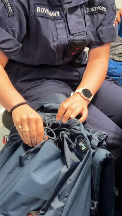 A person in Royal Navy cadet uniform opening a blue bag.
